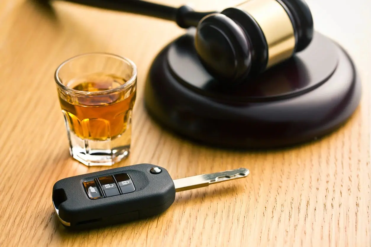 A car key, drink and gavel on the table.